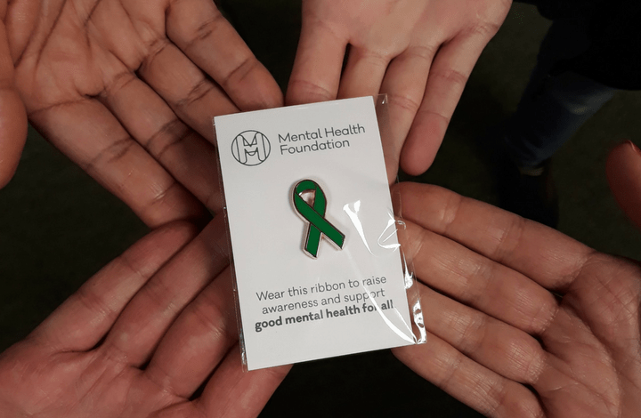 Green ribbon pin in hands
